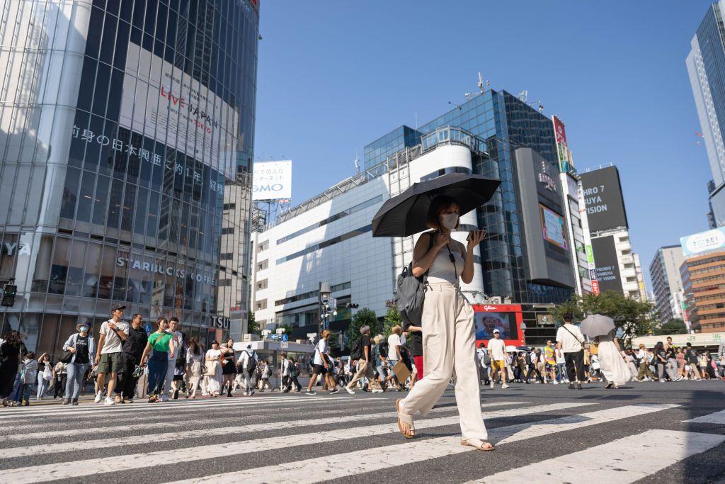Uma mulher atravessa a faixa de pedestres em T&oacute;quio