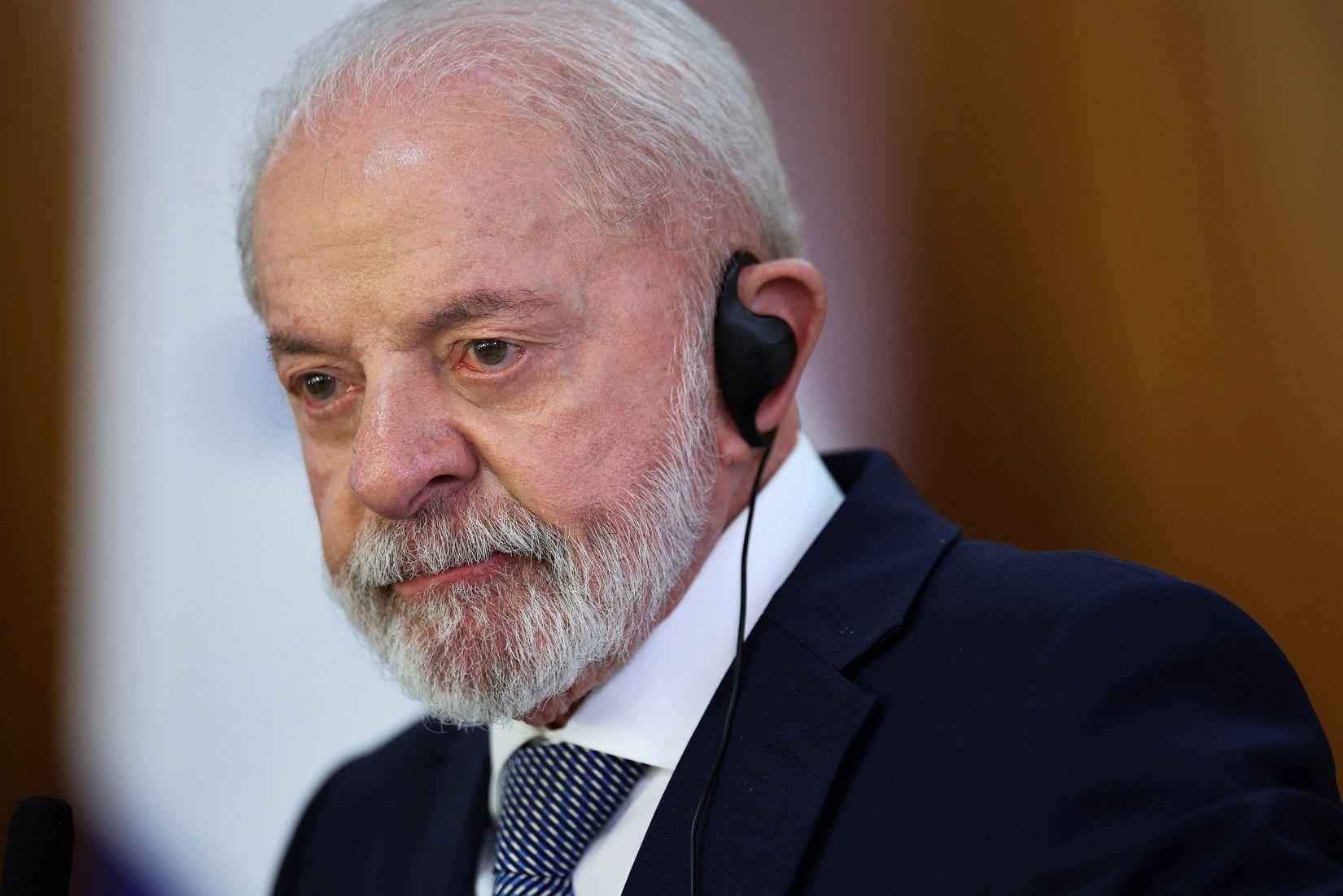 Lula com olhar sério, acompanhando reunião com fone de tradução