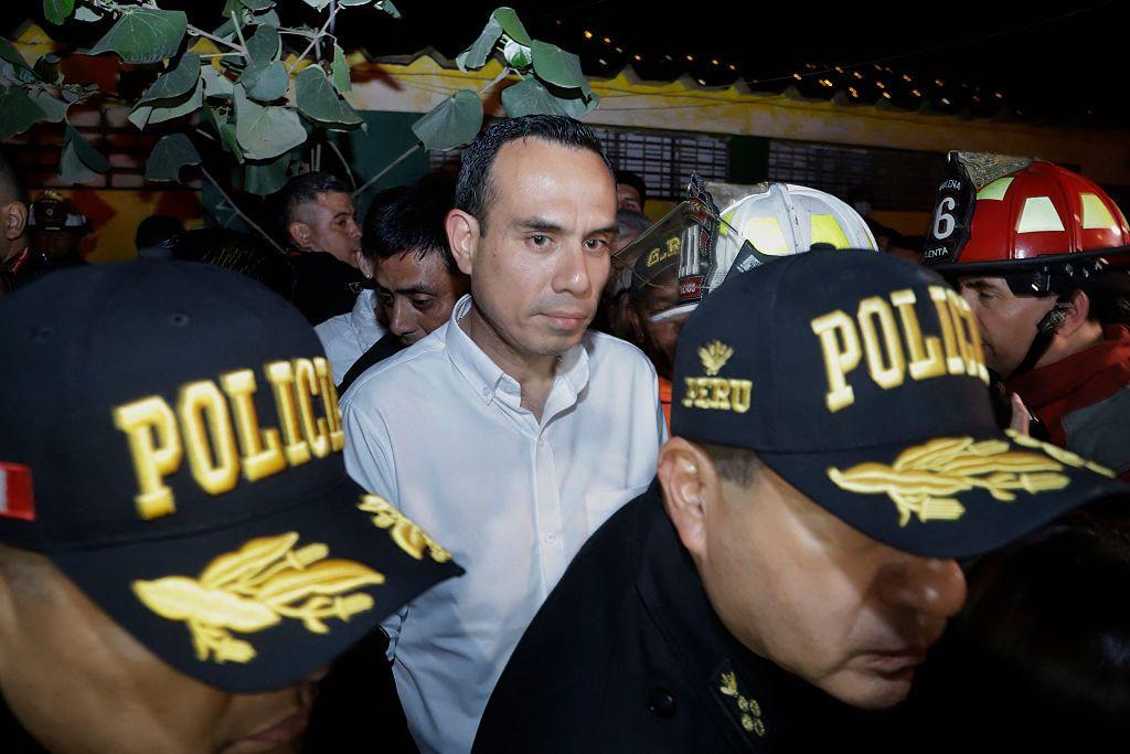 El presidente de Perú, José Jerí, tras dos policías, en una imagen nocturna. 