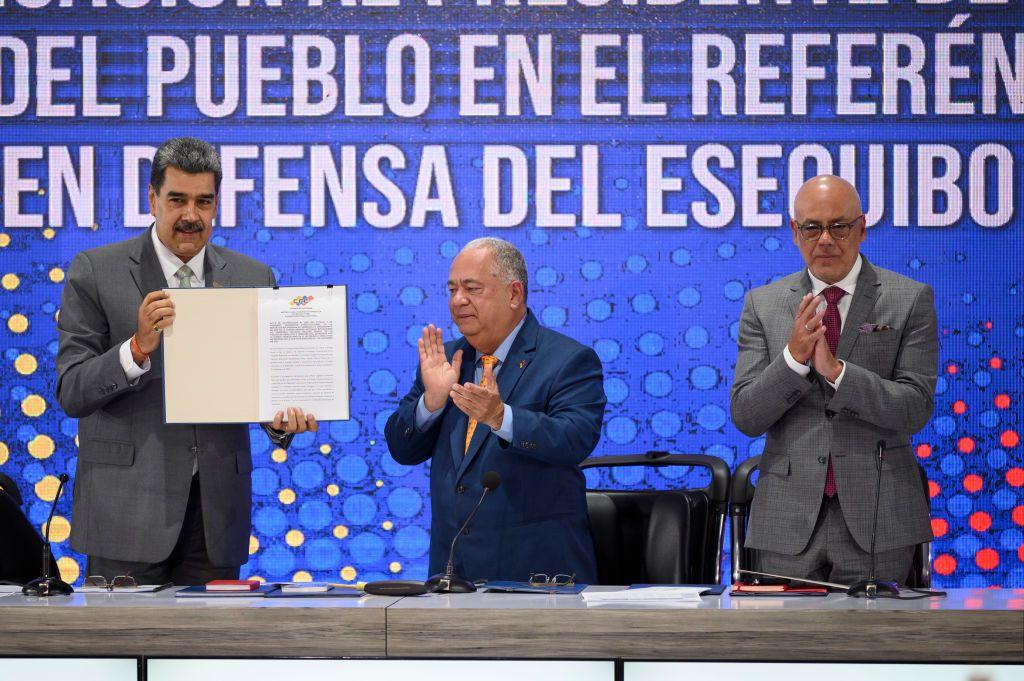 El presidente de Venezuela, Nicolás Maduro, el rector del Consejo Nacional Electoral, Elvis Amoroso, y el presidente de la Asamblea Nacional, Jorge Rodríguez, muestran el acta de notificación del referéndum durante una conferencia de prensa al día siguiente de que los venezolanos votaran en el referéndum sobre el conflicto fronterizo con el vecino país de Guyana sobre la potencial región petrolera del Esequibo el 11 de diciembre.