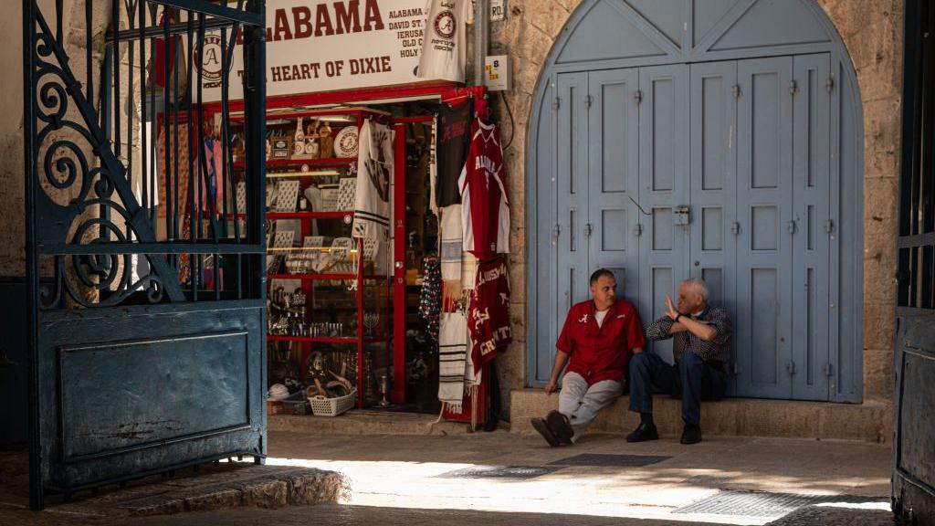 Dos hombres hablan en la puerta de un comercio en Jerusalén Este. 
