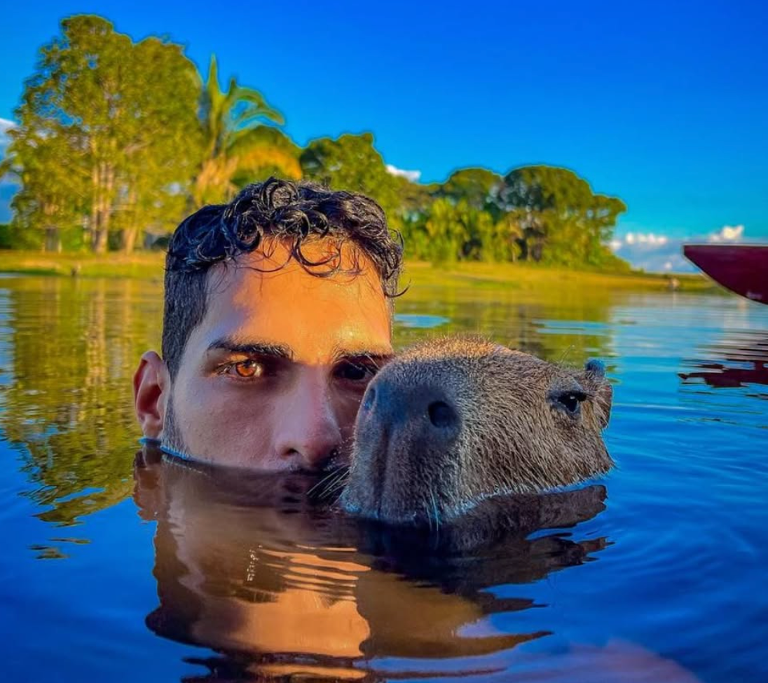 O influenciador Agenor Tupinambá e a capivara Filó com o corpo parcialmente coberto por água