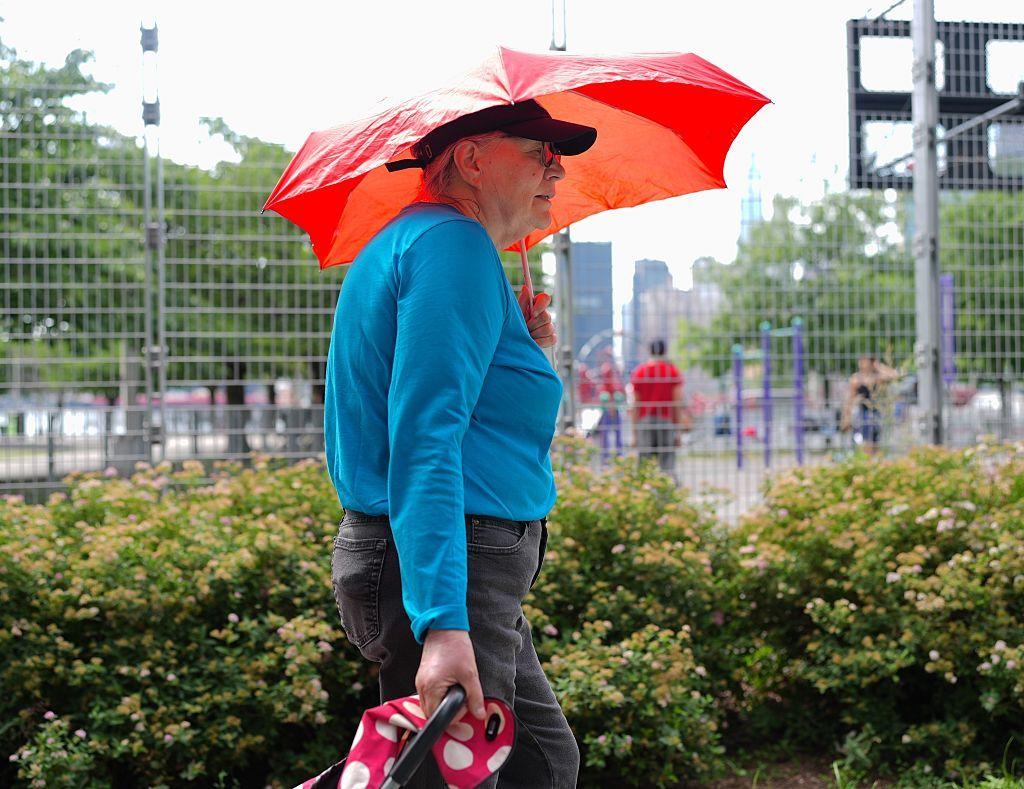 11 de junho de 2026. Uma idosa caminha com um guarda-chuva para se proteger do sol em Nova York, que estava sob alerta vermelho devido ao calor extremo.