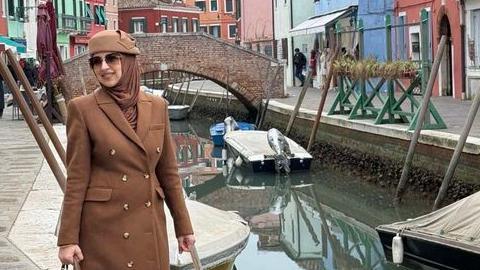 Žena u braon kaputu sa braon maramom i šeširom na glavi