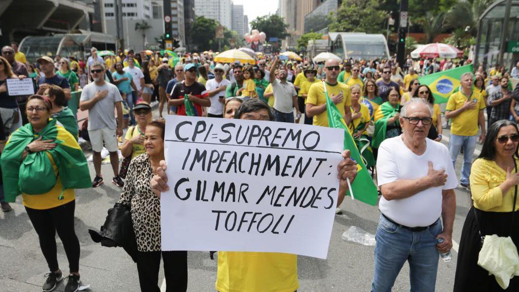 Manifestantes de verde e amarelo com um cartaz pedindo o impeachment dos ministros Gilmar Mendes e Dias Toffoli. 