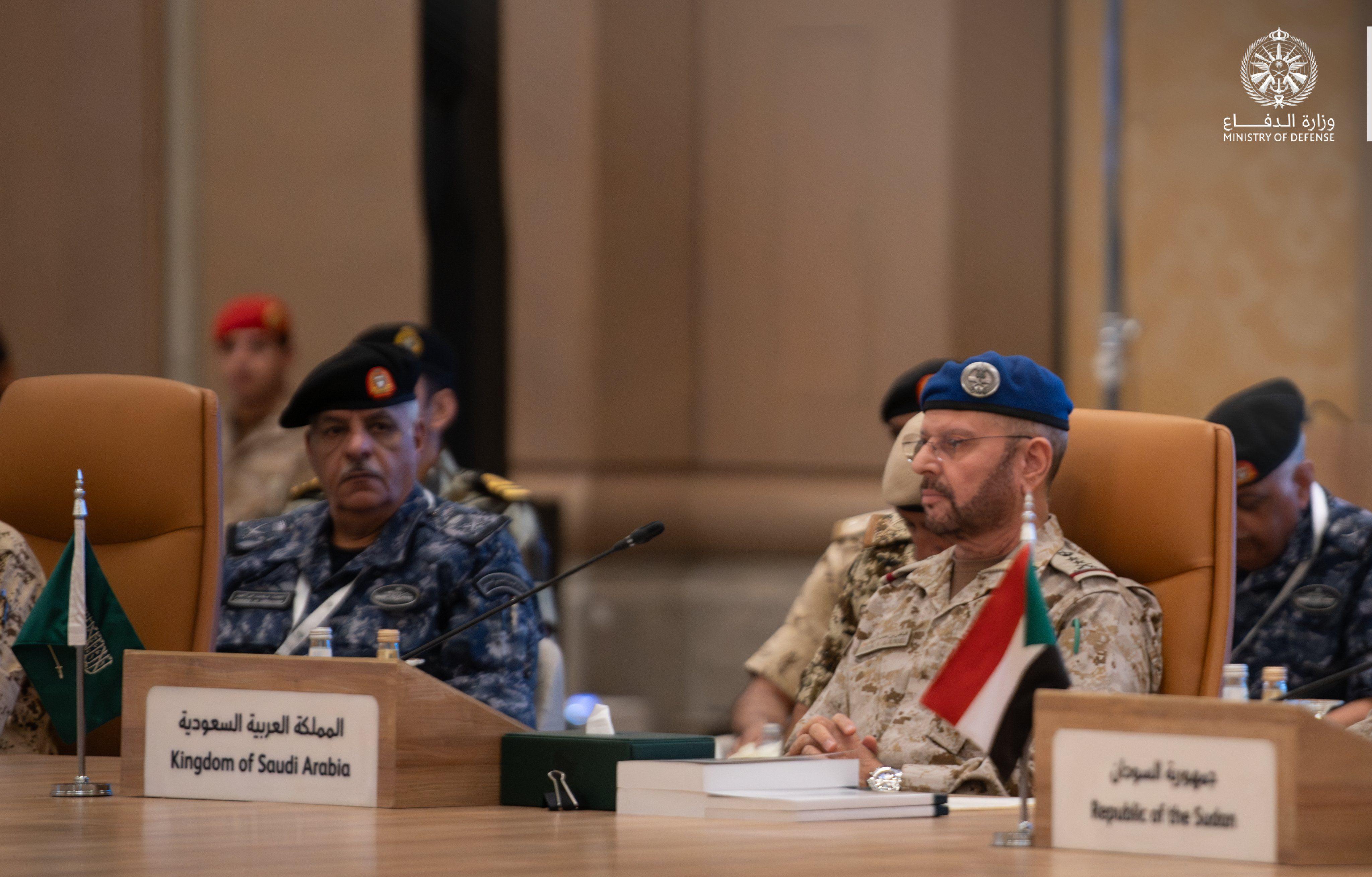 مسؤولون عسكريون يجلسون حول طاولة اجتماع، وأمامهم علما السعودية والسودان، خلال اجتماع بشأن التحالف البحري الدفاعي بقيادة السعودية