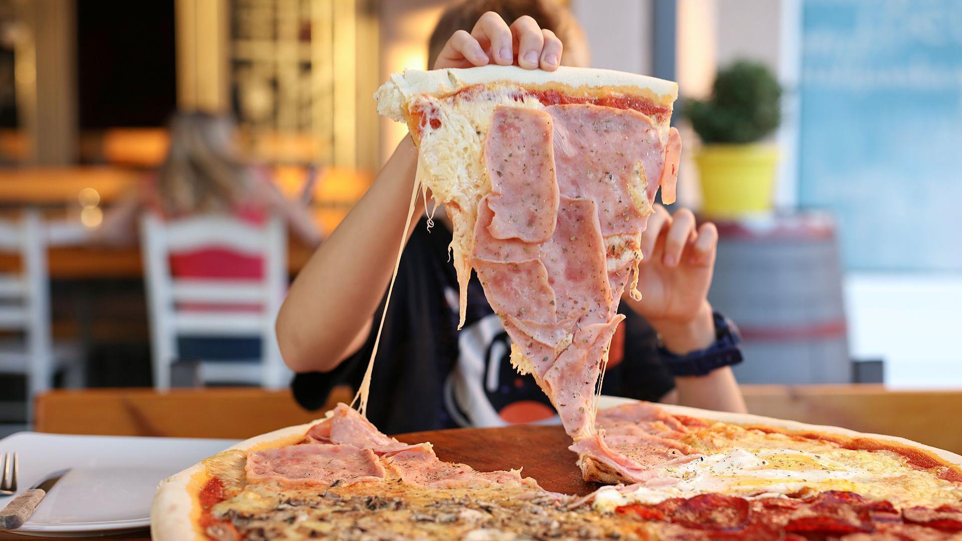 一位男孩拿起一大片披薩