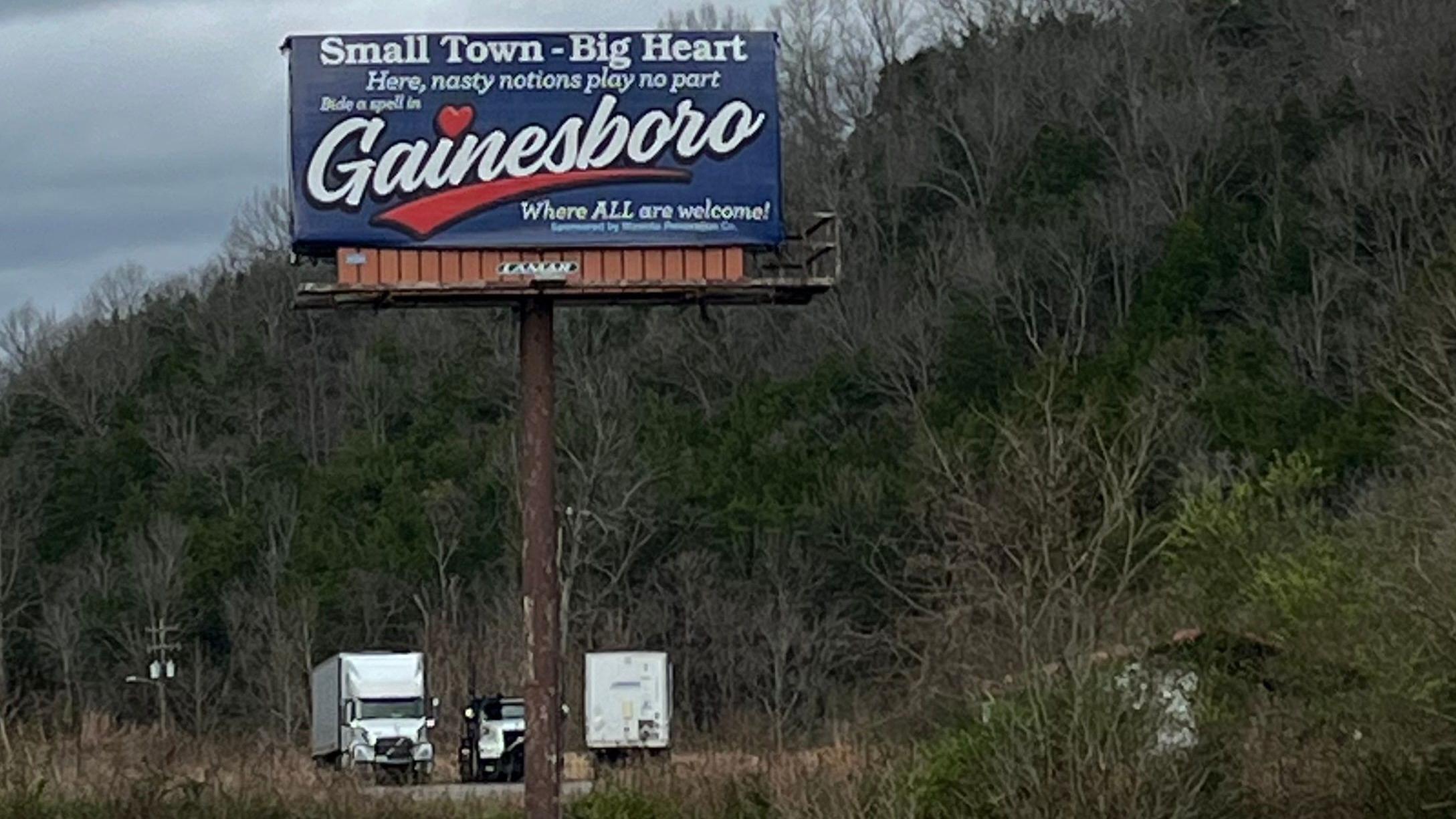 Outdoor em frente a uma estrada, com os dizeres em ingl&ecirc;s: 'Cidade pequena, grande cora&ccedil;&atilde;o, aqui n&atilde;o h&aacute; lugar para ideias nocivas. Gainesboro: onde todos s&atilde;o bem-vindos.'