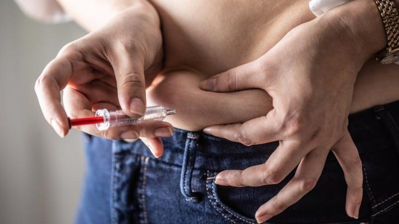 Mulher injetando com seringa na barriga