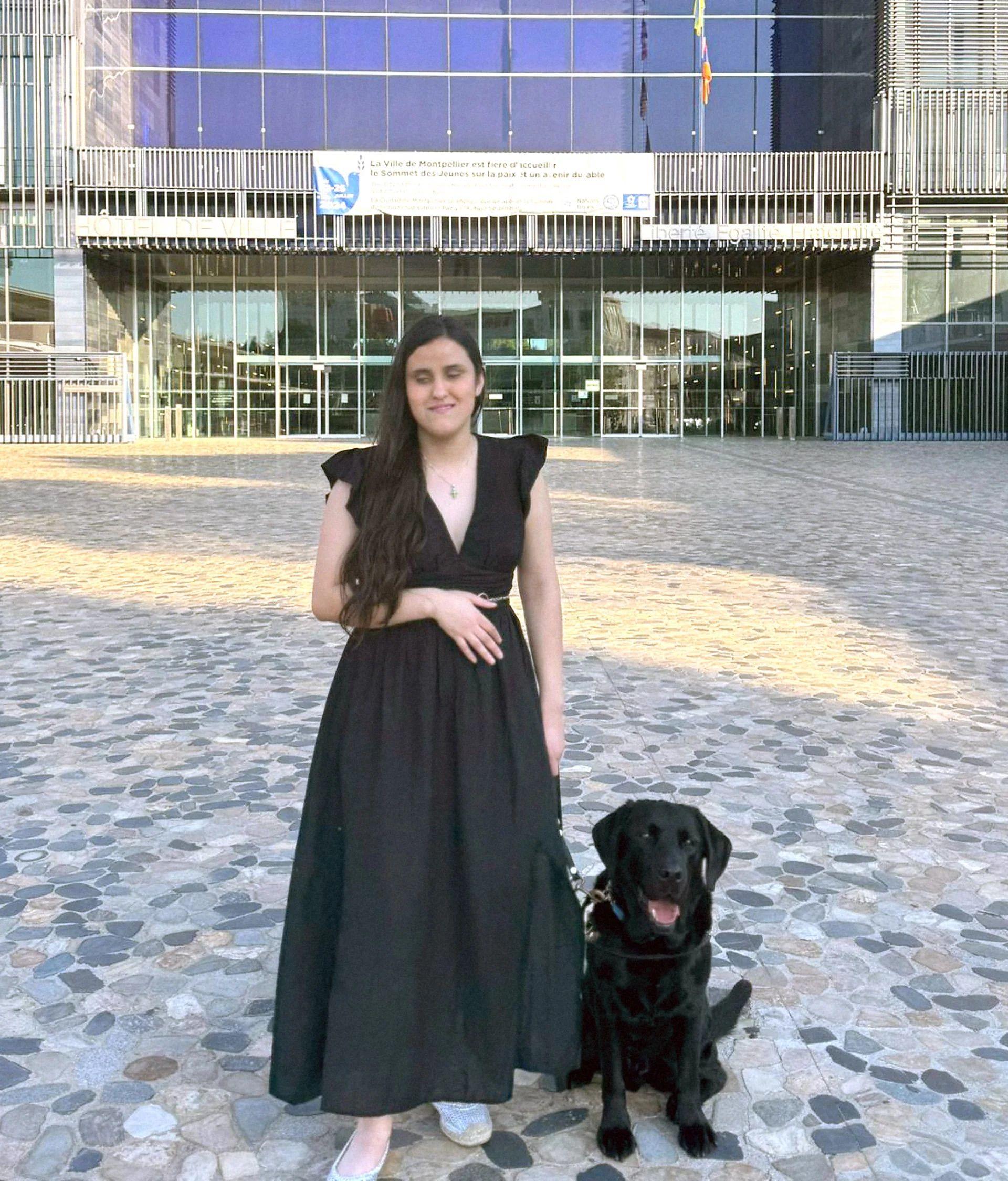 視障人士站在BBC總部大樓前，她牽著一隻黑色拉布拉多獵犬