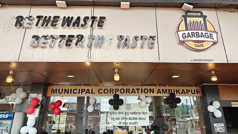 Entrada a una cafetería basura. Puede leerse en grandes letras "cuantos más residuos, mejor el sabor".