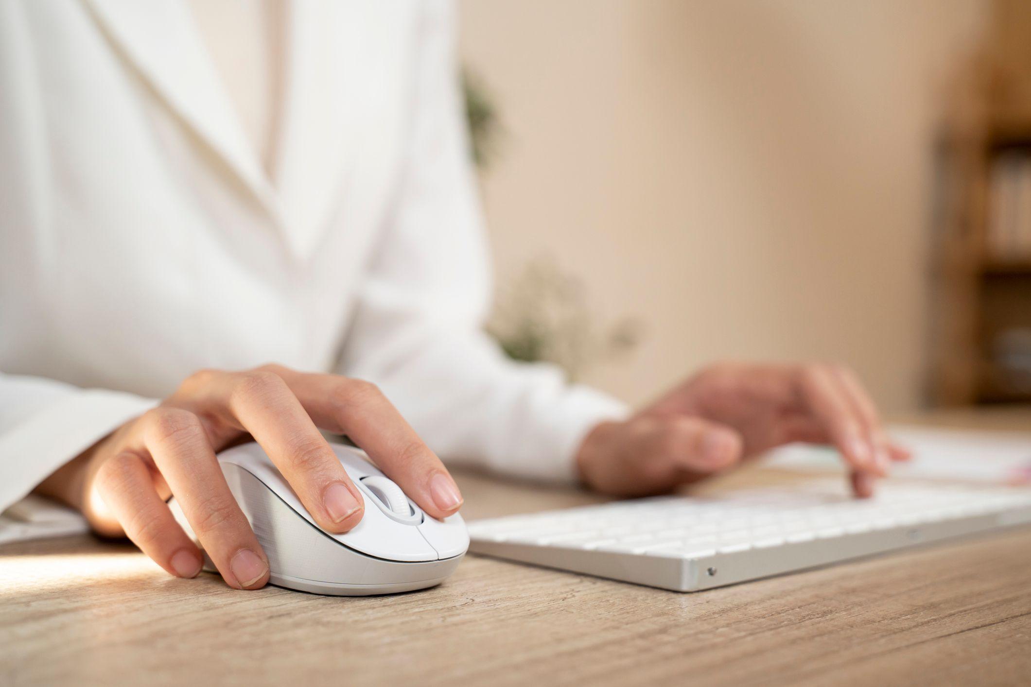 Mano de una mujer usando un mouse blanco