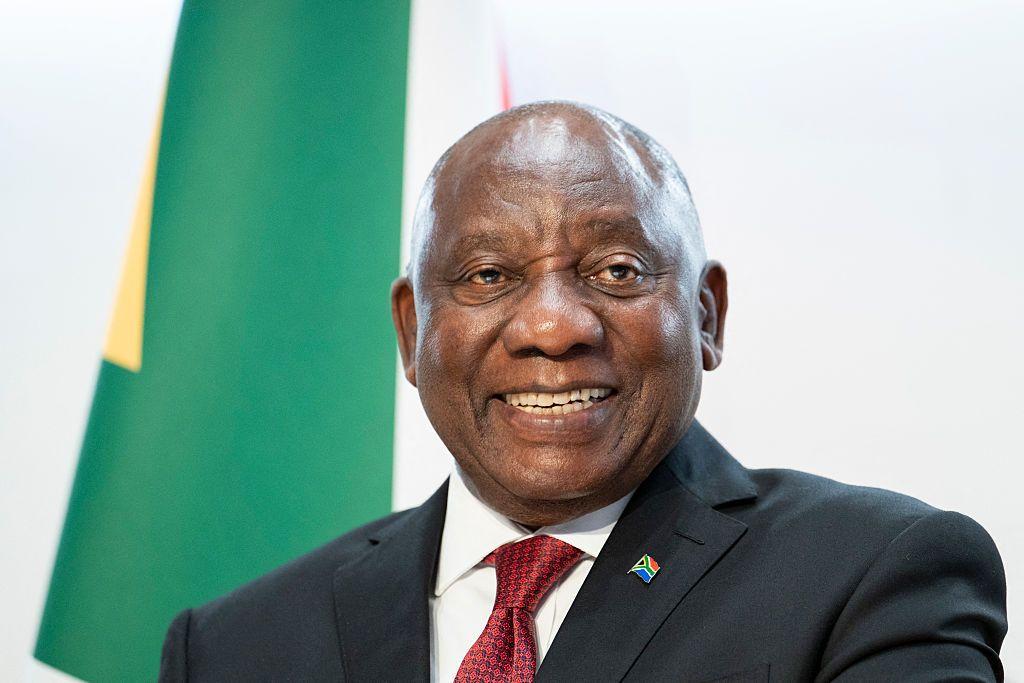 Cyril Ramaphosa, sonriente, con la bandera detrás