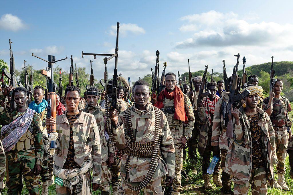 Un grupo de soldados somalíes de pie con sus armas apuntando al cielo. 