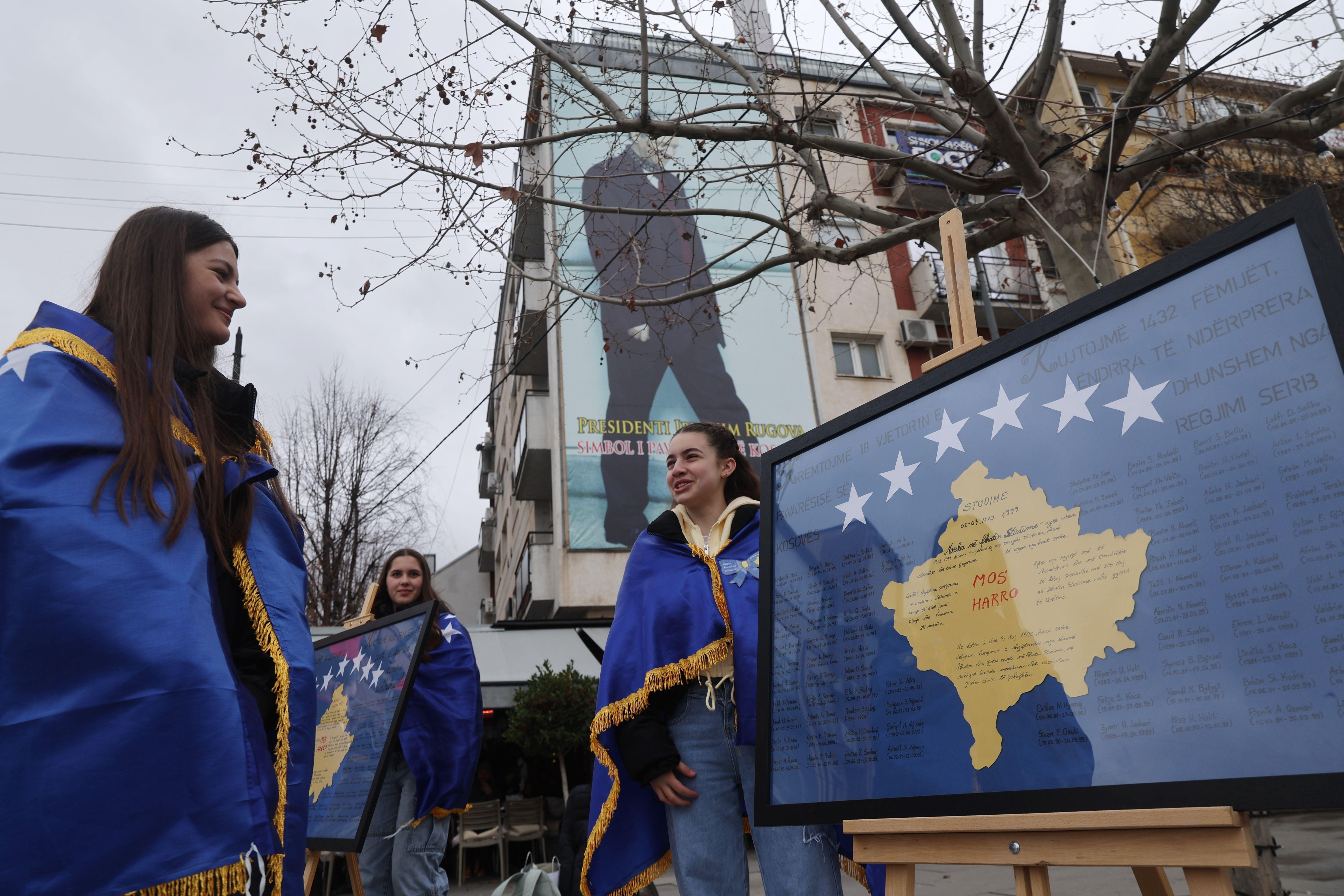 Devojke ogrnute kosovskim zastavama stoje pored panela sa imenima žrtava srpskog režima tokom proslave 18. godišnjice nezavisnosti zemlje u Prištini, Kosovo, 17. februara 2026. 