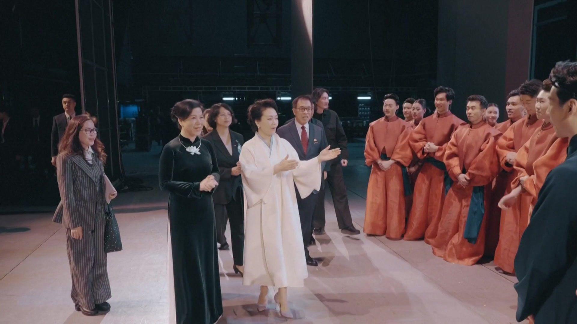 北京中國國家大劇院內彭麗媛（中，白衣者）向吳芳璃（左二，身穿黑色奧黛）介紹某演出項目的表演者（中國中央電視台片段截屏 15/4/2026）