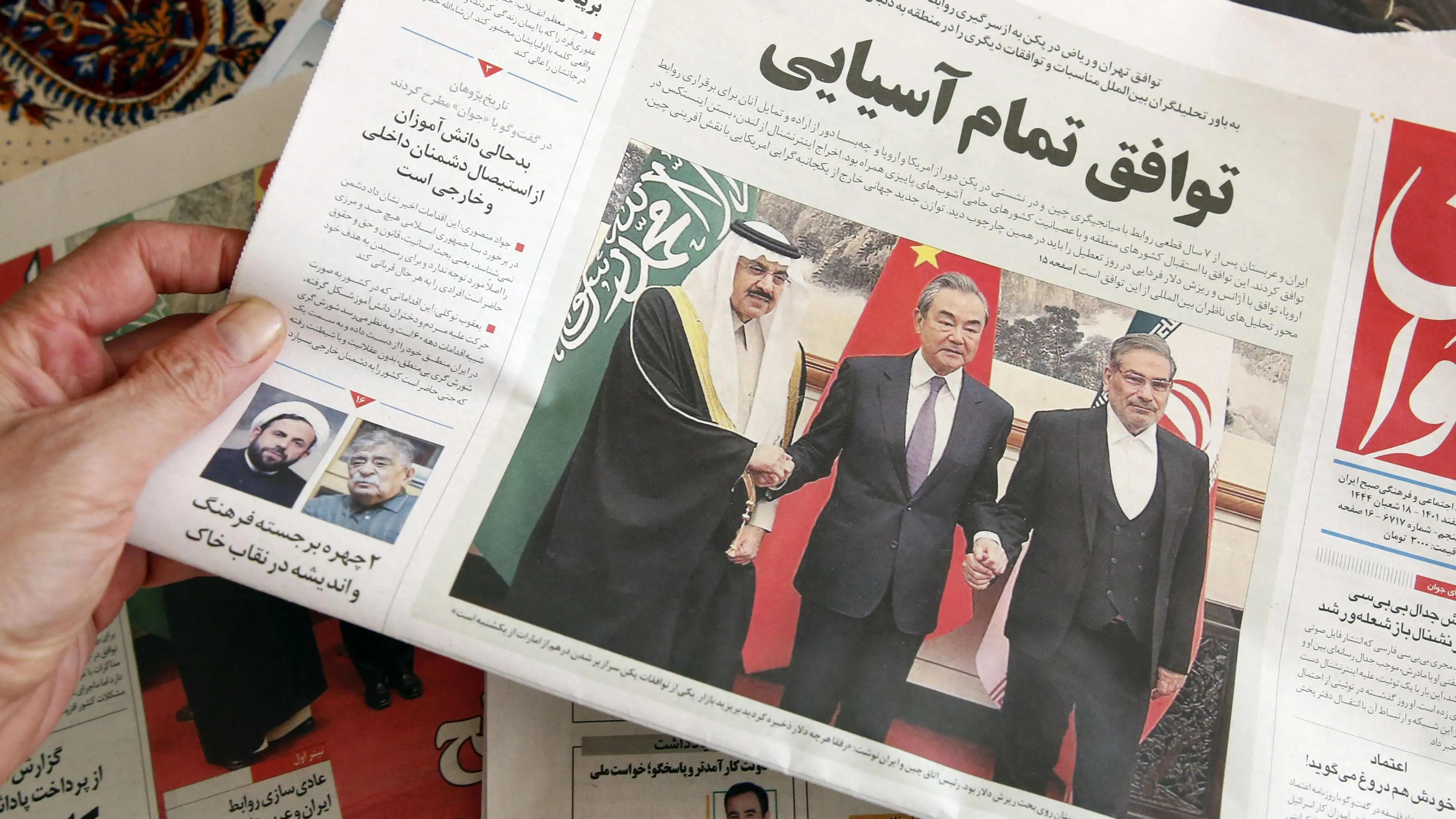 رجل في طهران يحمل صحيفة محلية تنشر على صفحتها الأولى تقريرا عن الاتفاق الذي توسطت فيه الصين بين إيران والمملكة العربية السعودية لاستعادة العلاقات، والذي تم توقيعه في بكين في اليوم السابق، 11 مارس/آذار 2023.