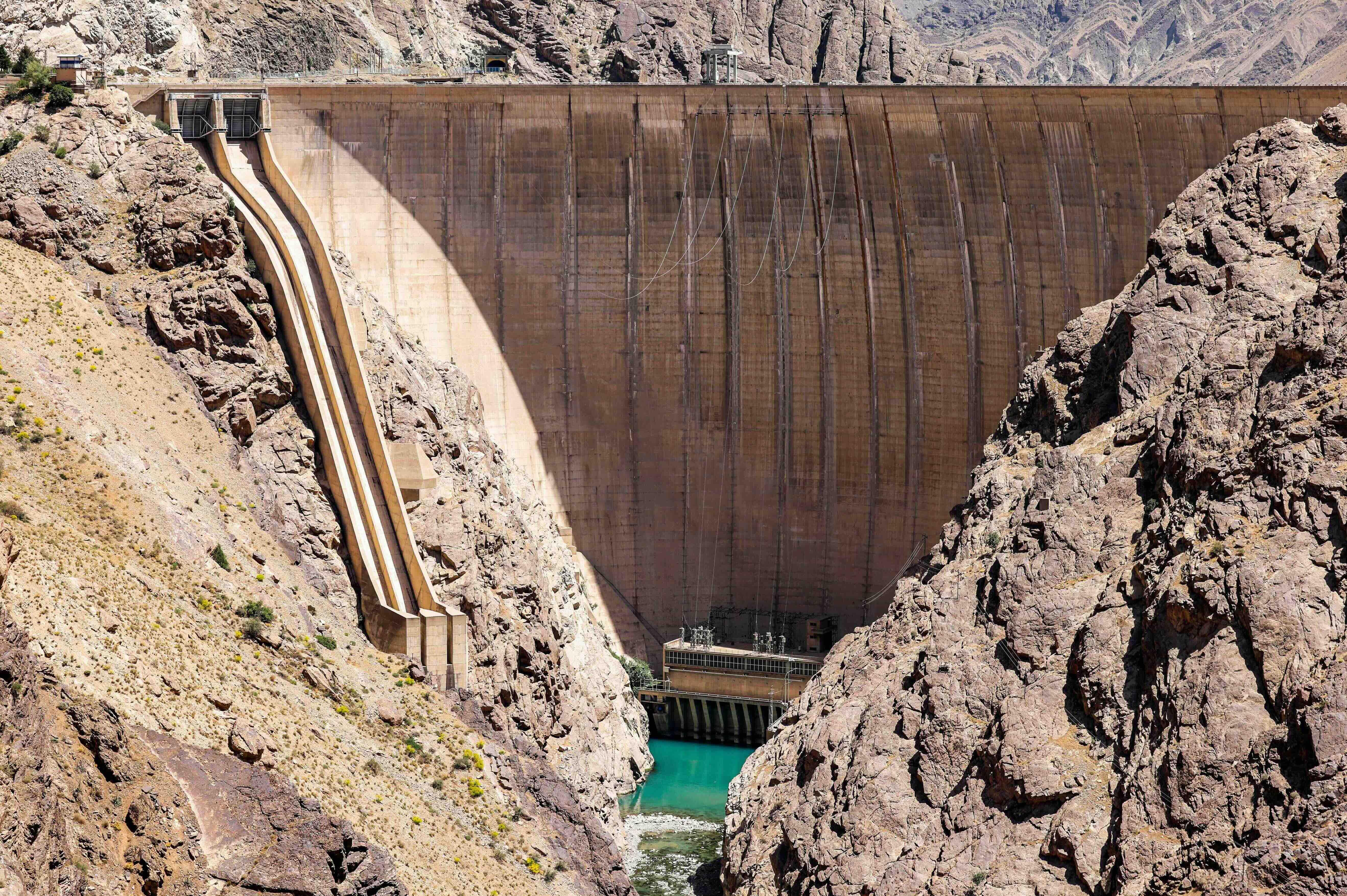 Entre las rocas se puede ver un embalse con bajo nivel de agua, con el muro de la presa Amir Kabir elevándose sobre la extensión de agua.