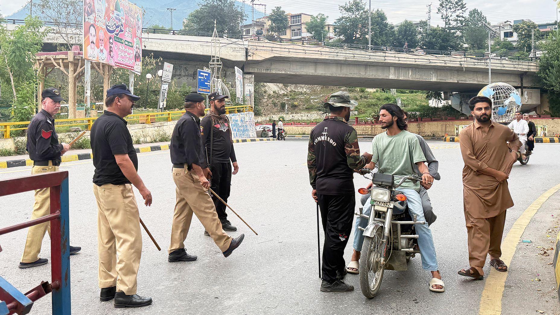 Police frisk people at a checkpoint in Muzaffarabad, the capital of Pakistan-administered Kashmir on July 15, 2026. Nine people were killed and a dozen wounded in renewed clashes between supporters of a banned protest group and security forces in Pakistan-administered Kashmir, an official said on July 15. (Photo by Sajjad QAYYUM / AFP via Getty Images)