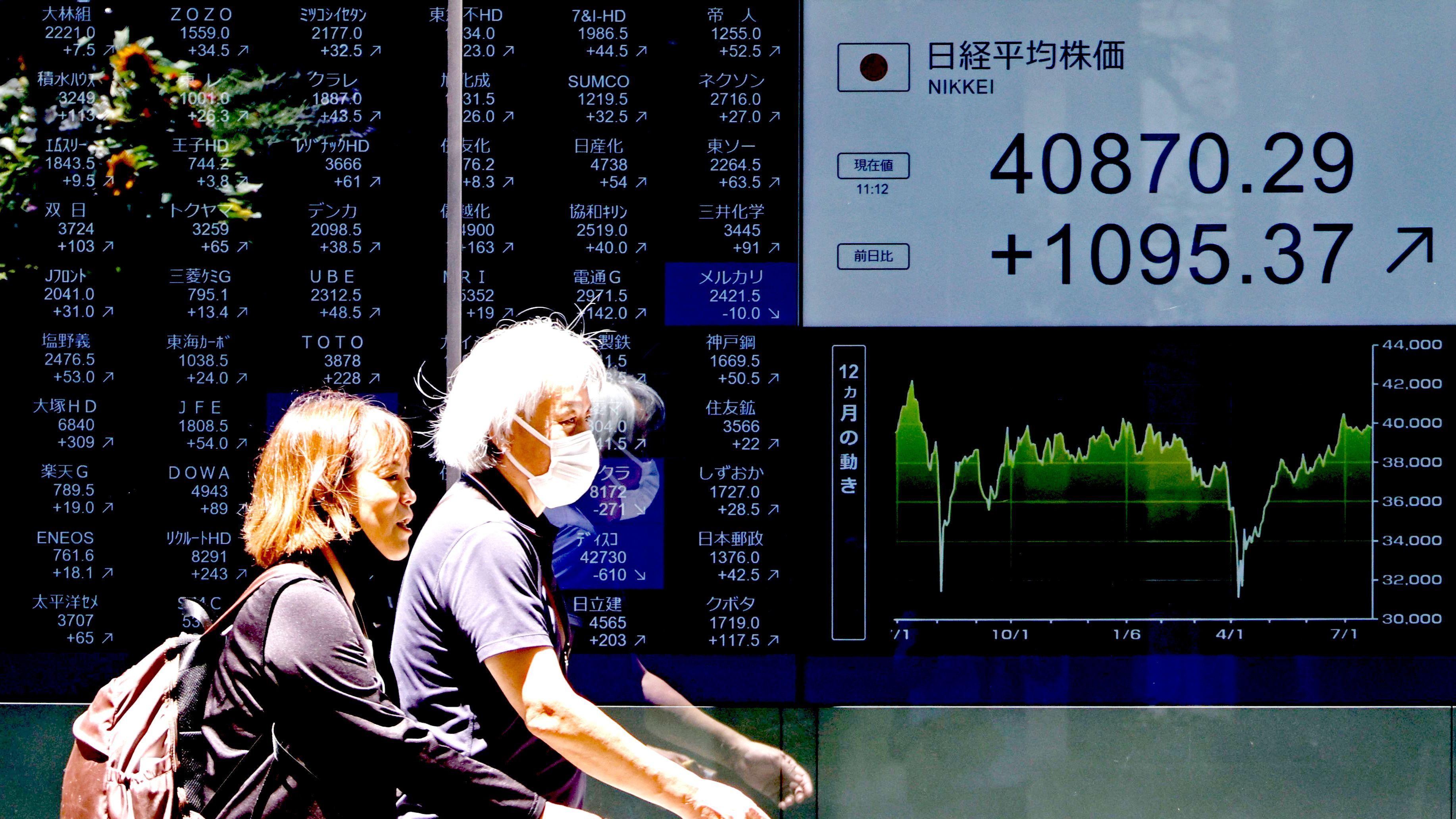 東京某金融機構外行人走過股市報價屏幕（23/7/2025）