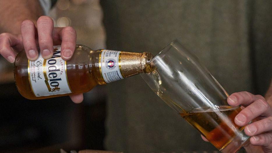 一個酒保把一瓶莫德羅（Modelo）啤酒倒進杯子裡