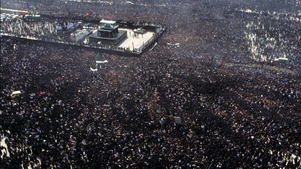 صورة من السماء: حشود غفيرة تحيط بمنصة وُضع عليها جثمان روح الله الخميني، خلال مراسم تشييعه التي بدأت في طهران في 5 يونيو/حزيران 1989، قبل دفنه في اليوم التالي.
