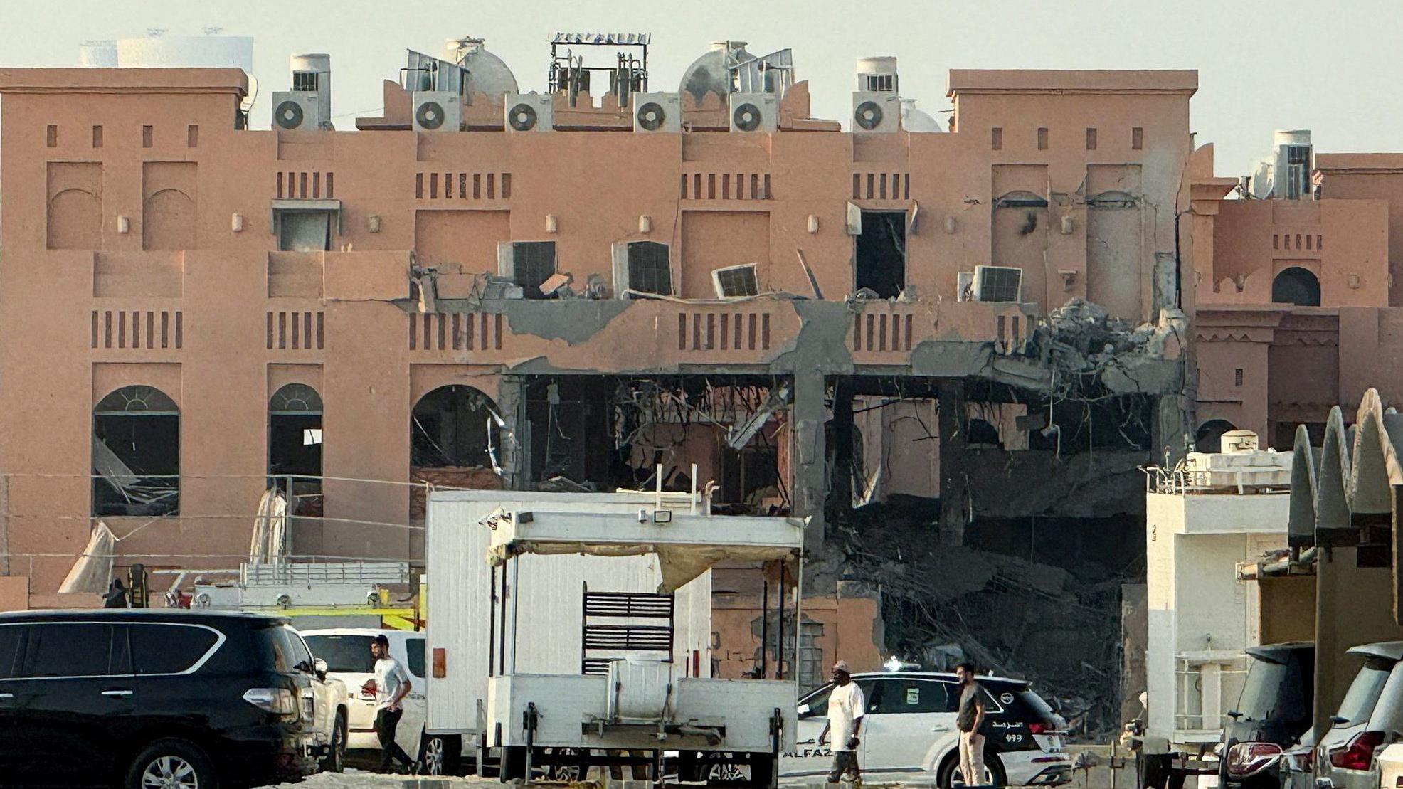 مبنى متضرر في أعقاب هجوم إسرائيلي على قادة لحماس في الدوحة مع وجود سيارة شرطة وسيارات أخرى وعدد من الأشخاص.