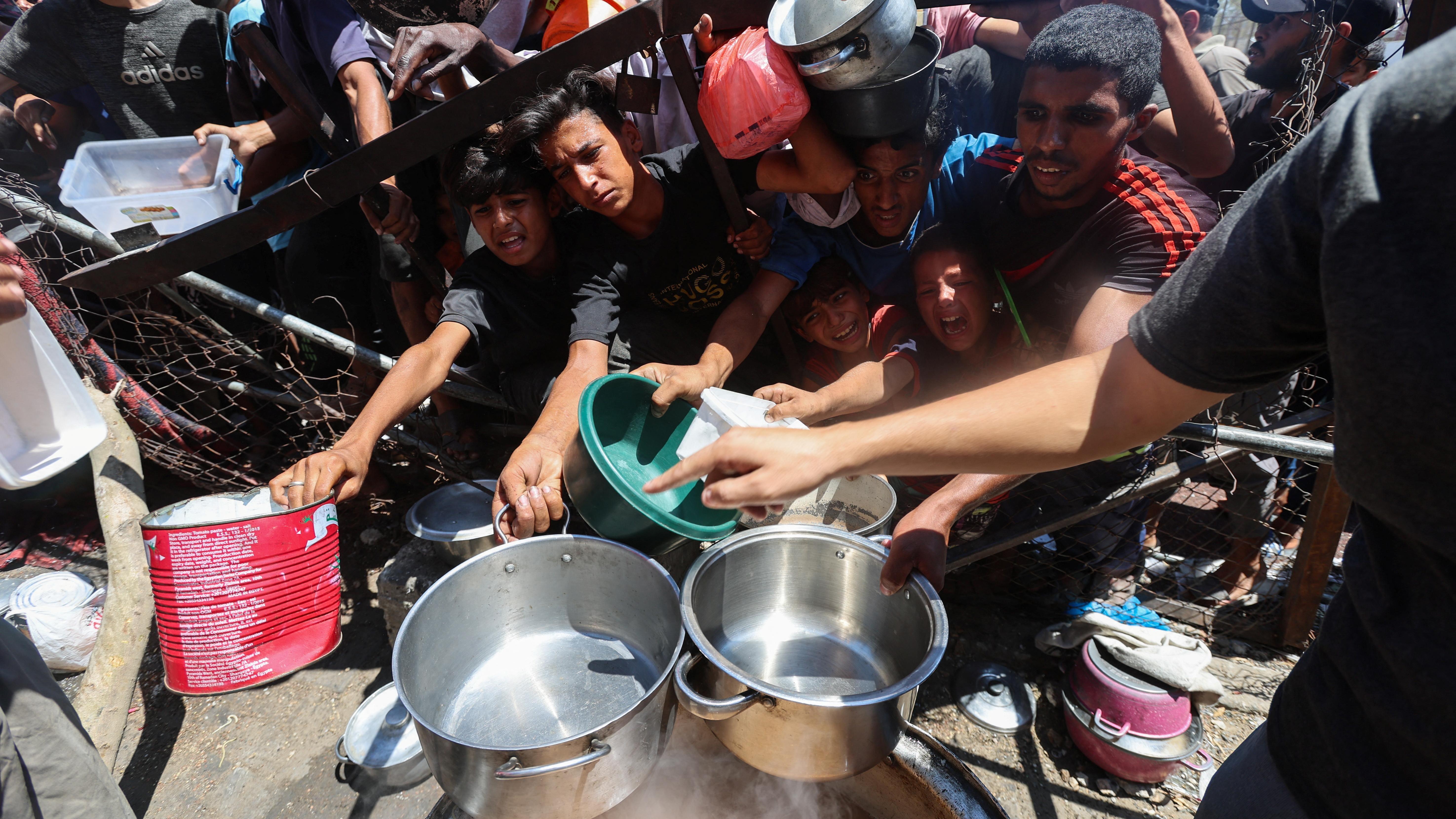 فلسطينيون يتجمعون لتلقي الطعام من مطبخ خيري، وسط أزمة جوع، في النصيرات، وسط قطاع غزة