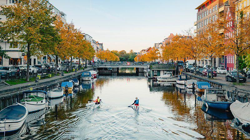 Imagem de canal de Copenhague, na Dinamarca, com barcos e pessoas andando de caiaque