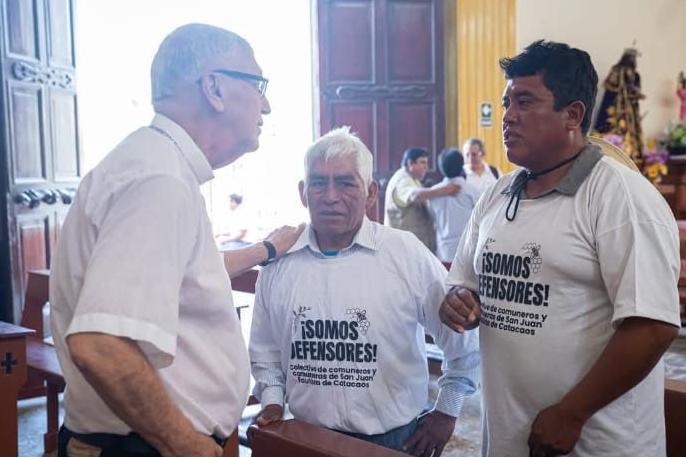 Miembros de la comunidad de Catacaos visten camisetas con el lema "somos defensores" mientras conversan con representantes de la iglesia Católica.