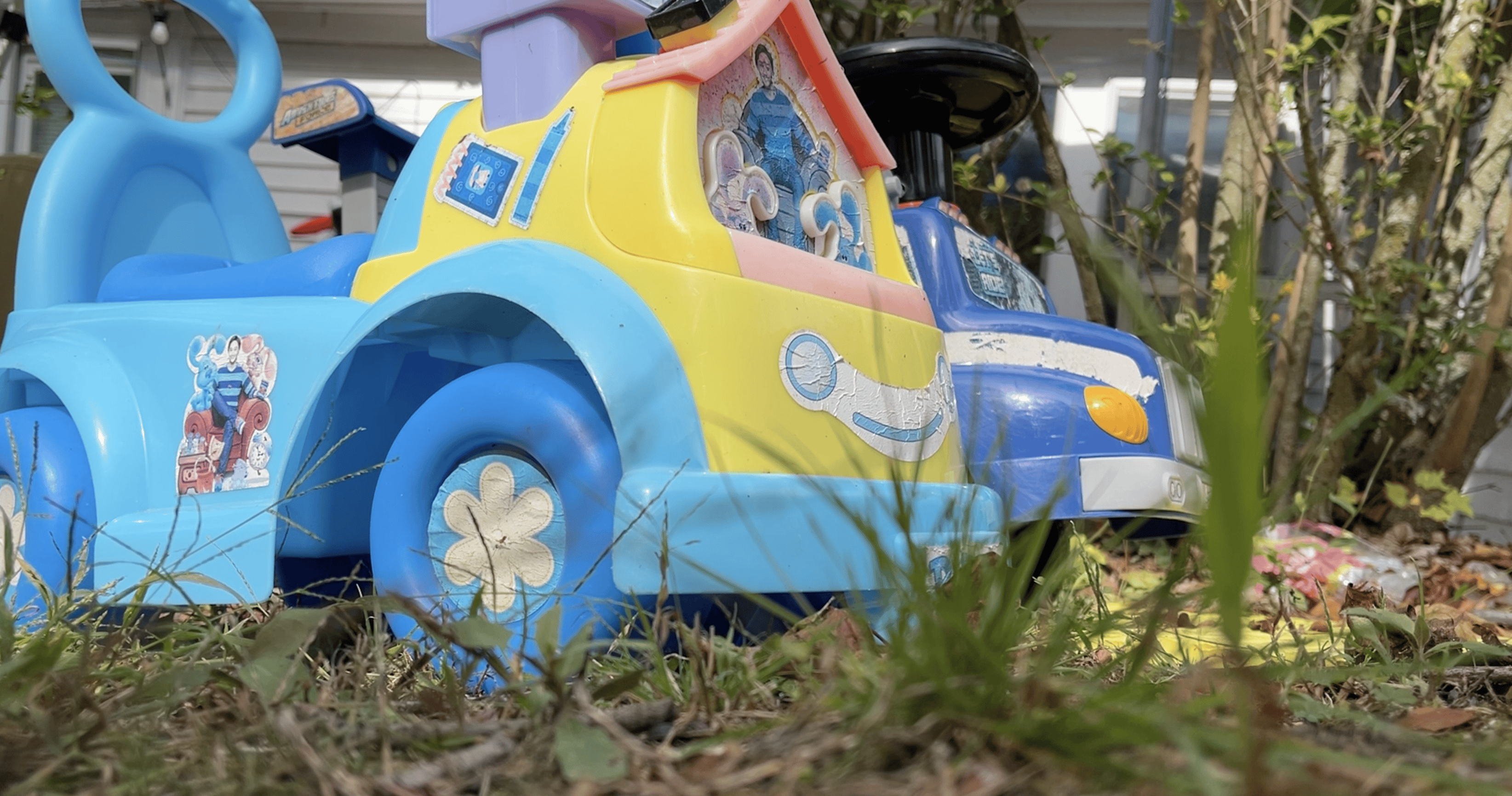 Um carrinho de brinquedo azul coberto por grama verde