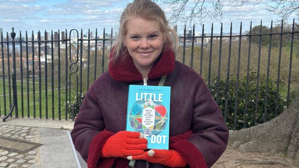Mujer joven rubia sosteniendo libro con manos con guantes rojos y con chaqueta de piel vinotinto