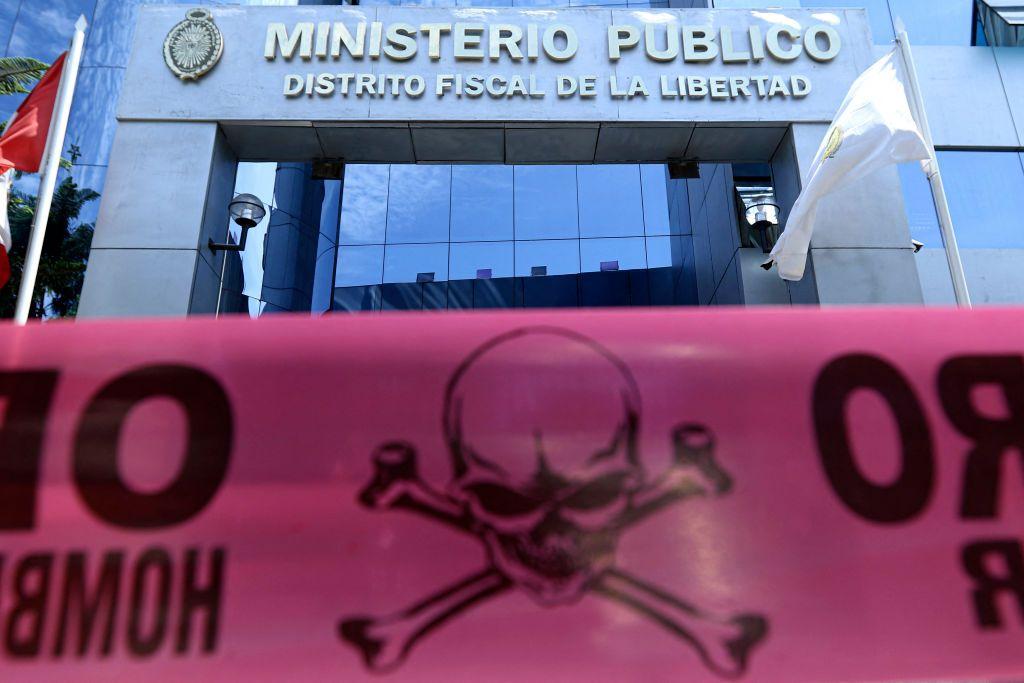 Fachada donde se lee "Ministerio Público", "Distrito Fiscal de La Libertad". Frente ella, una cinta plástica con una calavera y dos tibias.