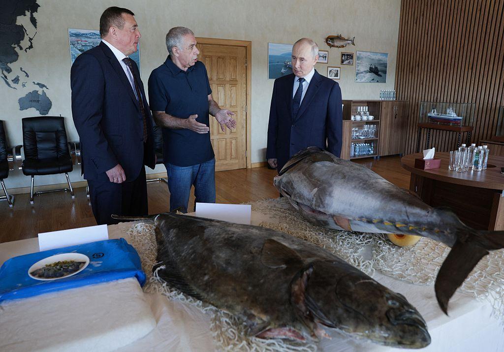 En esta fotografía de grupo distribuida por la agencia estatal rusa Sputnik, el presidente de Rusia, Vladímir Putin, visita la planta de procesamiento de pescado Yasny, en la isla de Iturup.