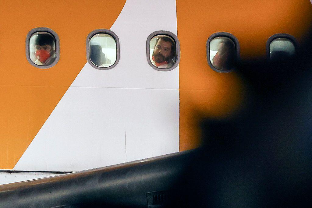 Personas miran por la ventana en el vuelo que llevò a 261 personas a El Salvador de EE.UU.