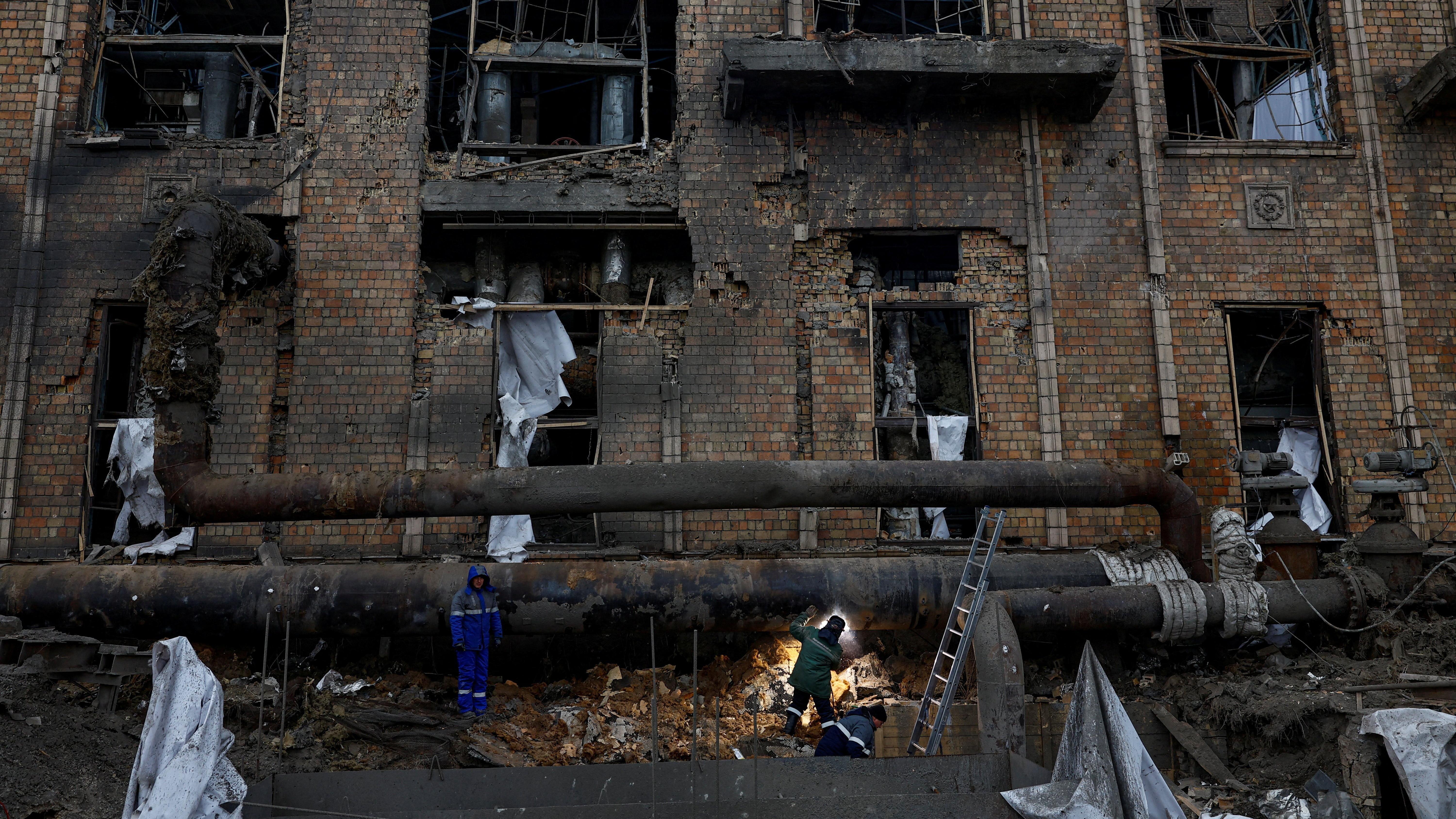 عُمال يُصلحون أنبوباً في مجمع محطة دارنيتسيا الحرارية للطاقة، التي تضررت بشدة جراء غارات صاروخية وطائرات مسيرة روسية حديثة، وسط الهجوم الروسي على أوكرانيا، في كييف، أوكرانيا، 4 فبراير/شباط 2026. 