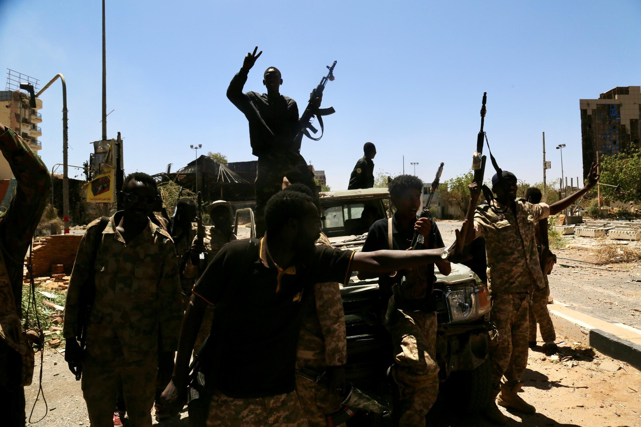 صورة توضح مجموعة من القوات التي تدعم الجيش السوداني، مع وجود ضابط جيش يقف بينهم حاملاً بندقية