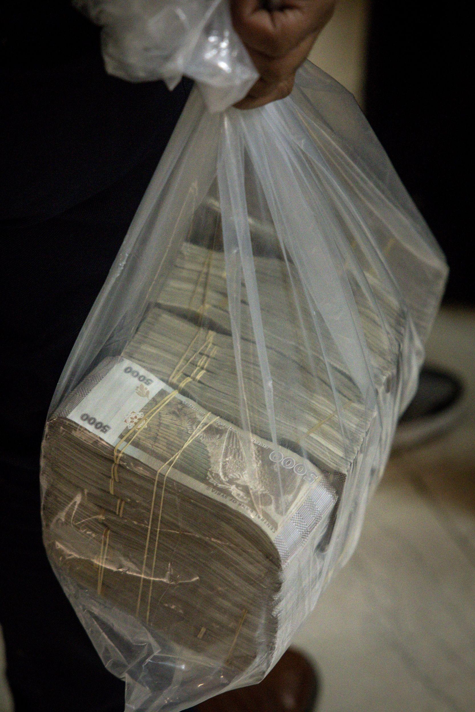 رجل يحمل كيساً من الليرات السورية بعد استبدال الدولار الأمريكي في مصرف سوريا المركزي في 24 ديسمبر/كانون الأول 2024