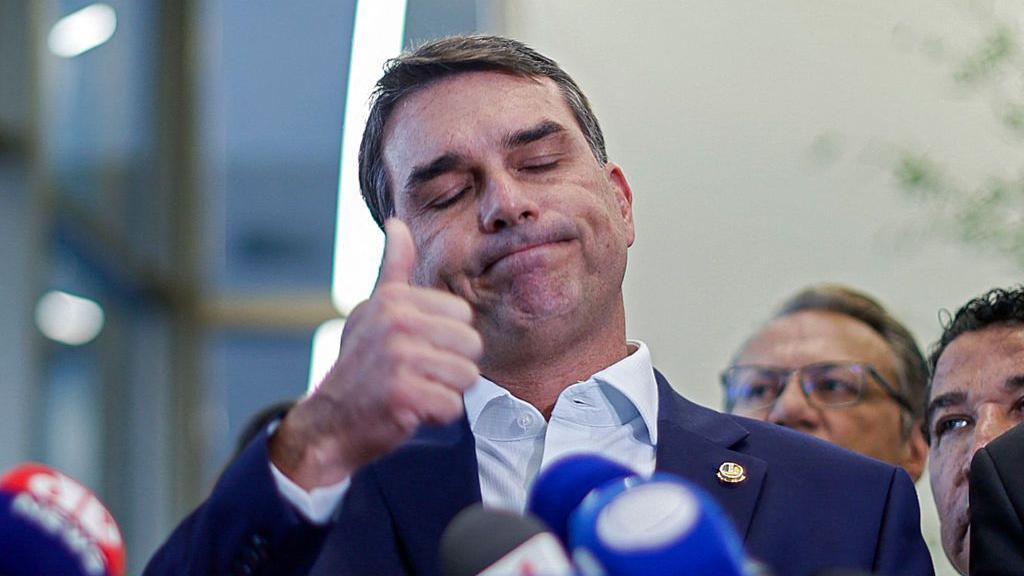 O senador Fl&aacute;vio Bolsonaro, pr&eacute;-candidato &agrave; presid&ecirc;ncia e filho do ex-presidente Jair Bolsonaro, faz um sinal de positivo com o polegar enquanto fala sobre sua rela&ccedil;&atilde;o com Daniel Vorcaro, que financiou o filme 