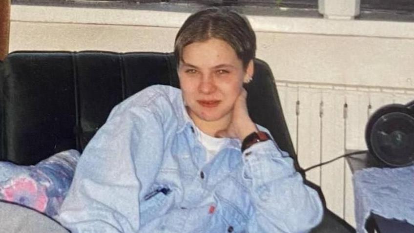 A woman sat on a sofa in a denim-like jacket. 