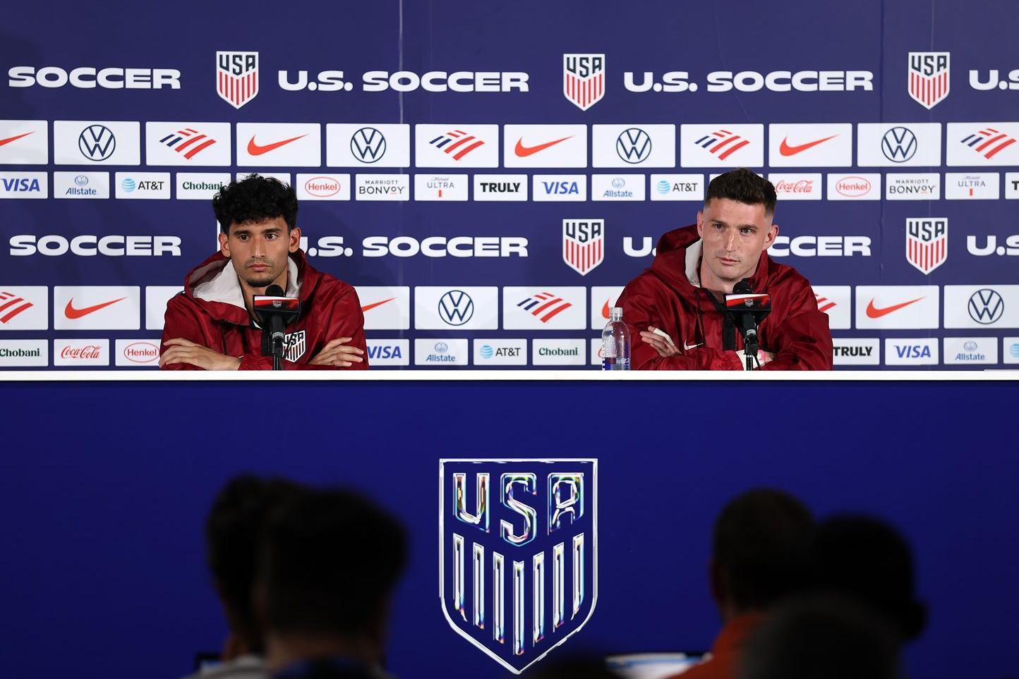 Ricardo Pepi e Matthew Freese, da sele&ccedil;&atilde;o americana de futebol, durante entrevista  coletiva na Calif&oacute;rnia, nos Estados Unidos, em frente aos microfones e tendo atr&aacute;s uma parede repleta de escudos dos Estados Unidos e logotipos de patrocinadores