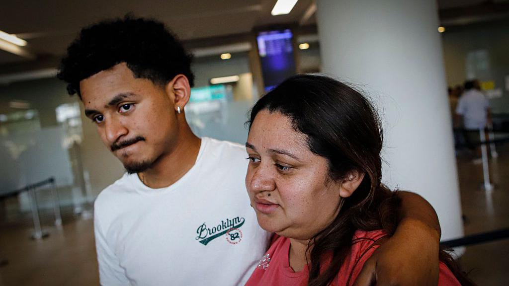 Emerson Colindres abraza por el cuello a su madre, Ada Baquedano, en el aeropuerto de Tegucigalpa, Honduras, el 24 de junio de 2025.  (Foto: JORGE CABRERA/AFP via Getty Images)
