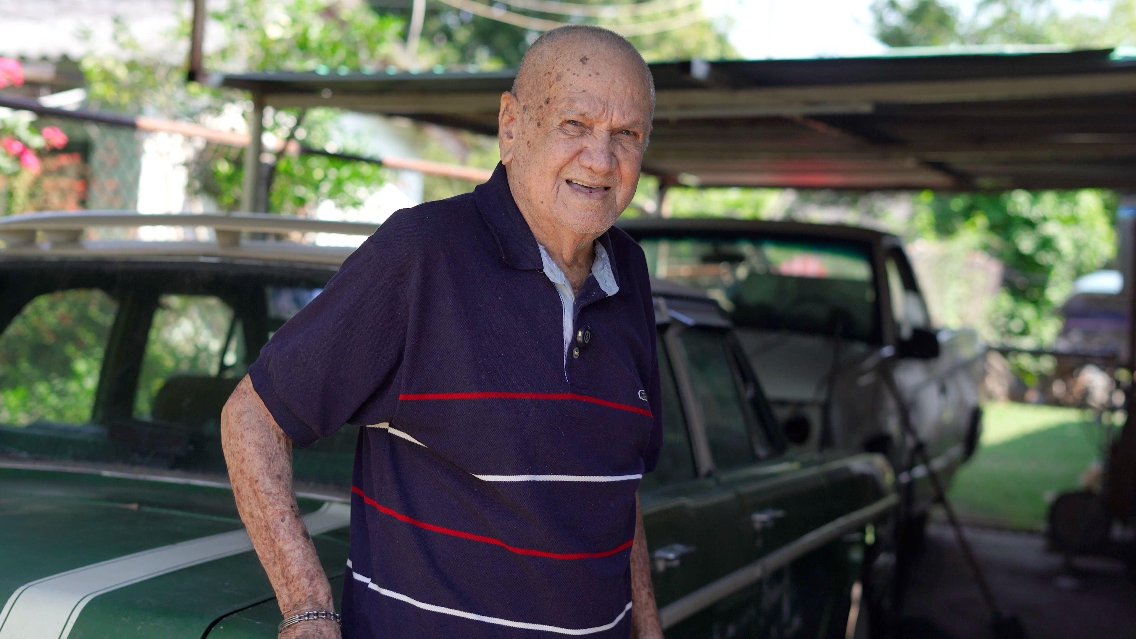 José Rodas delante de su Dodge Dart de color verde.