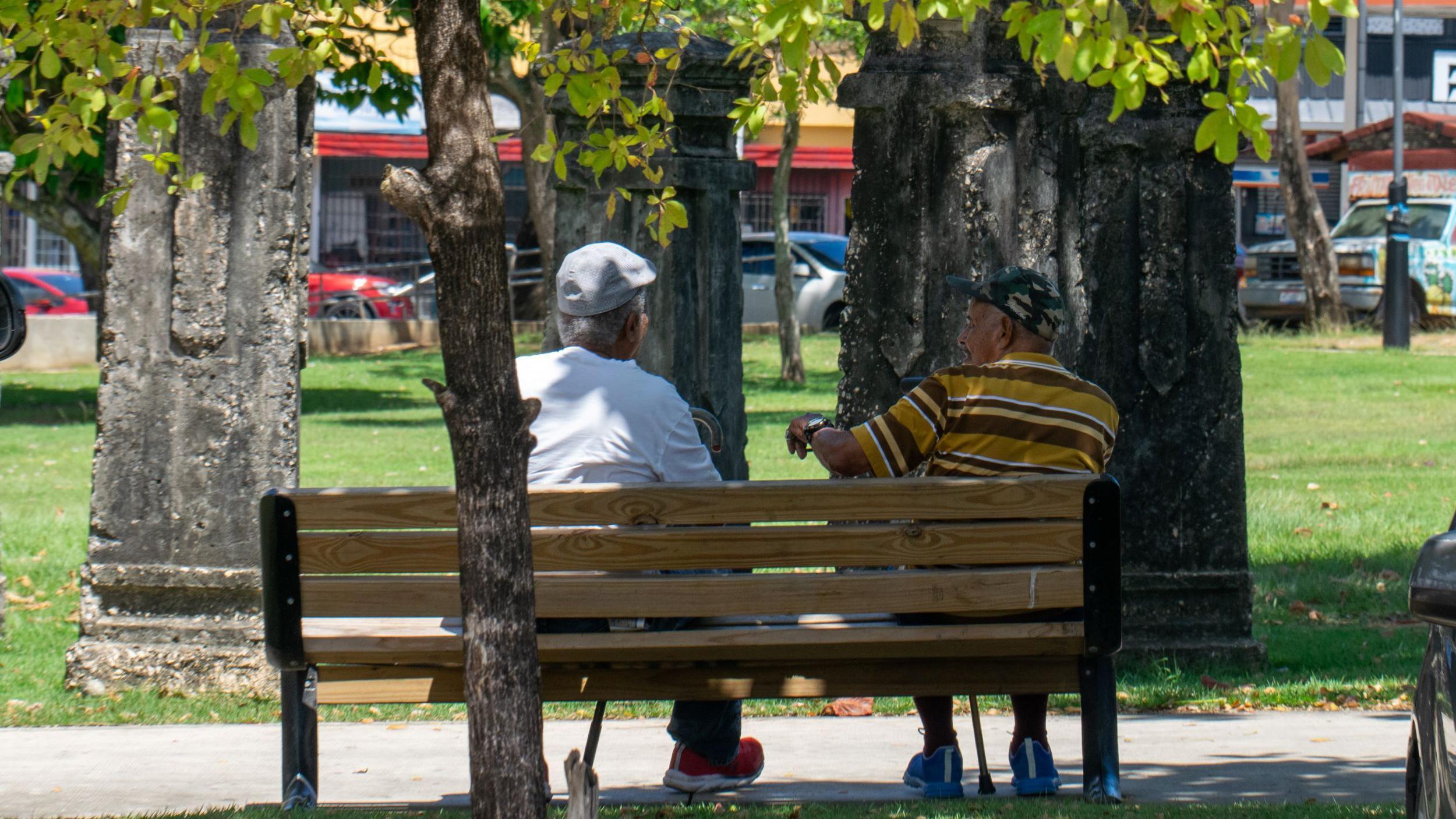 dos hombres sentados en una plaza de barrio obrero, en San Juan, Puerto Rico