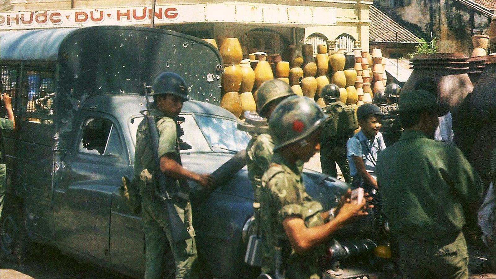 Imagen de varios soldados en las calles de saigón. Se ve jimmy al fondo sentado entre los militares.