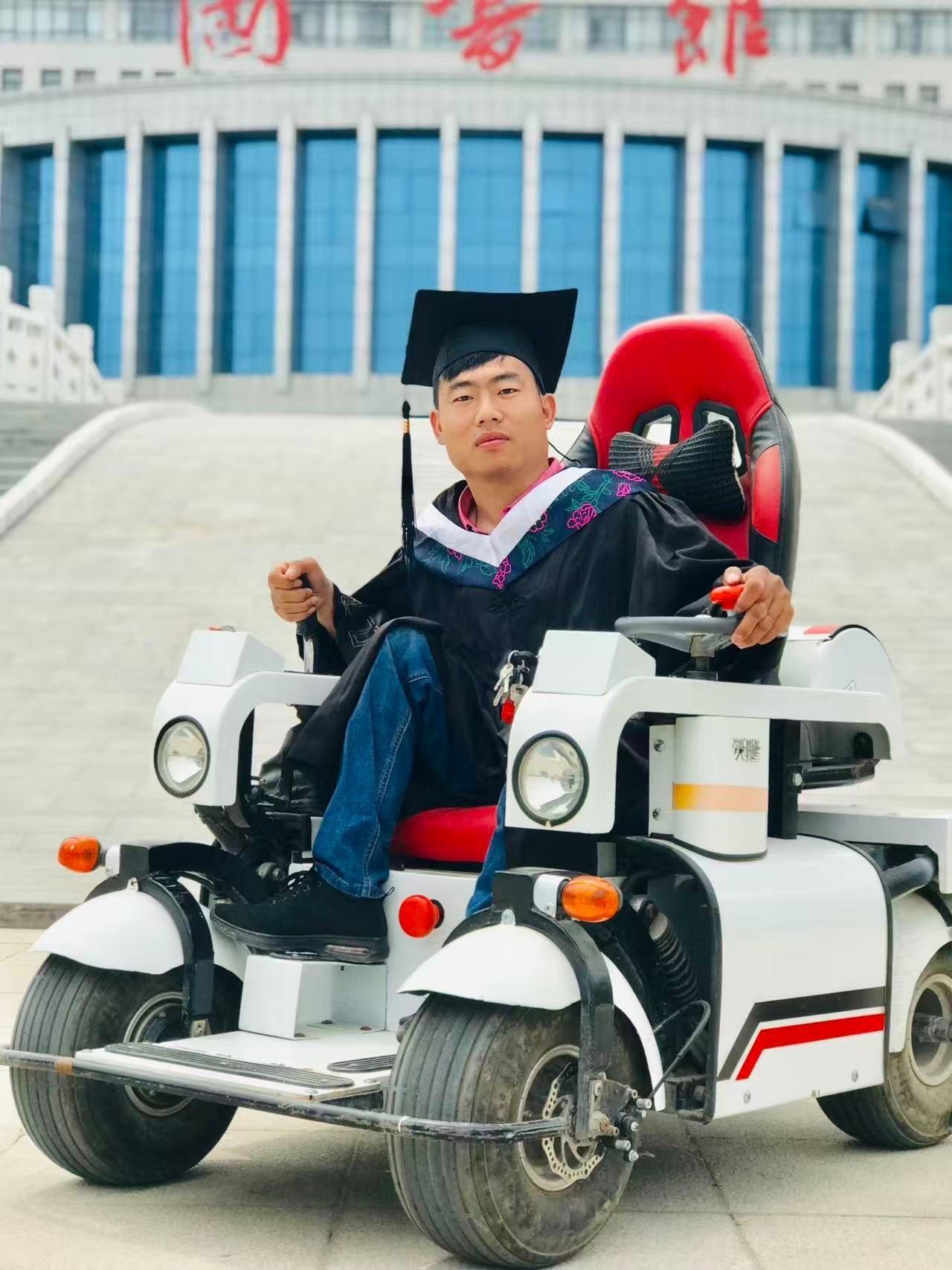 El doctor Li en su graduación, vestido con la toga y el birrete negros, sentado en su scooter de movilidad