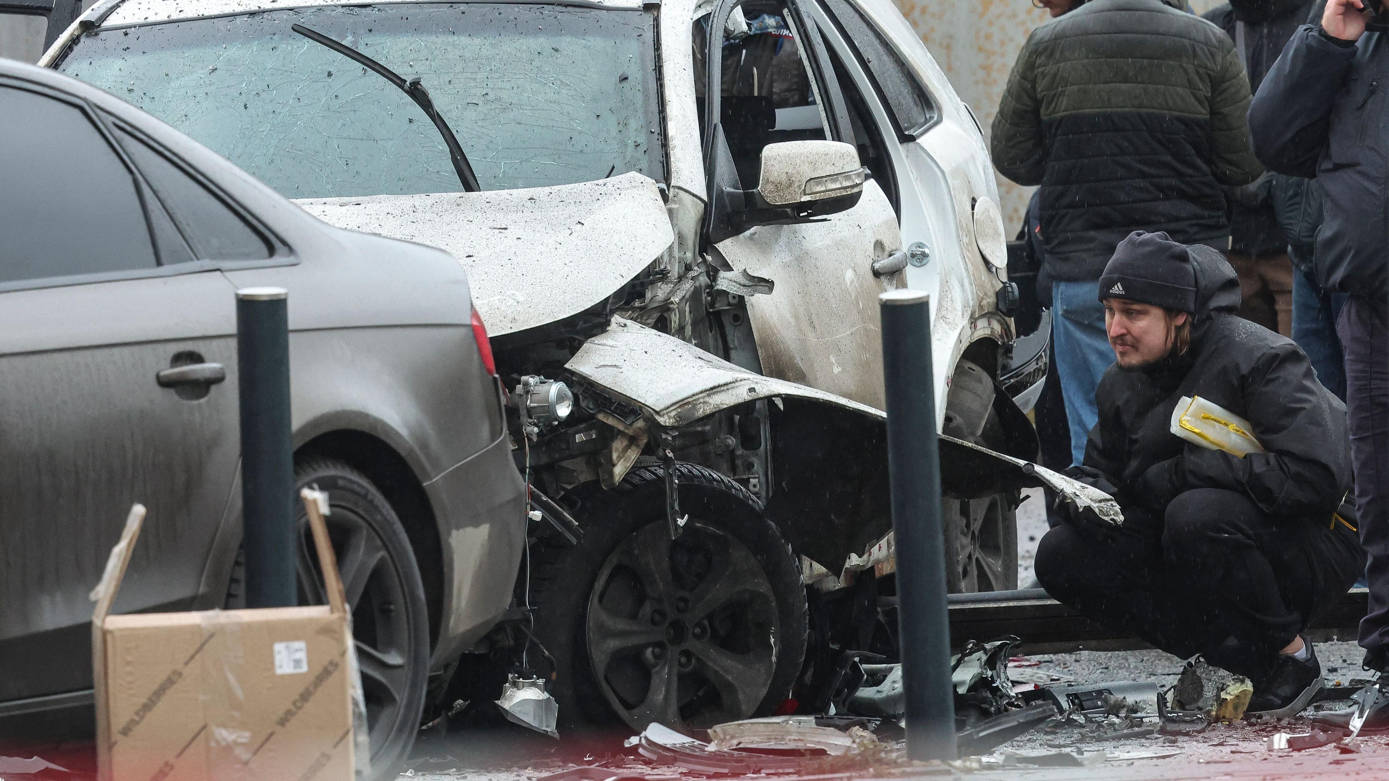 
Investigadores trabalham perto de um carro destru&iacute;do ap&oacute;s a explos&atilde;o de um artefato explosivo.
