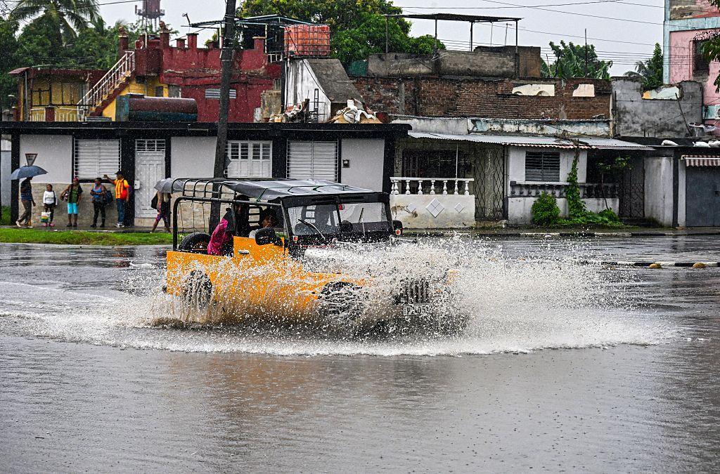 Un vehículo cruza una calle inundada en la ciudad de Santiago de Cuba.