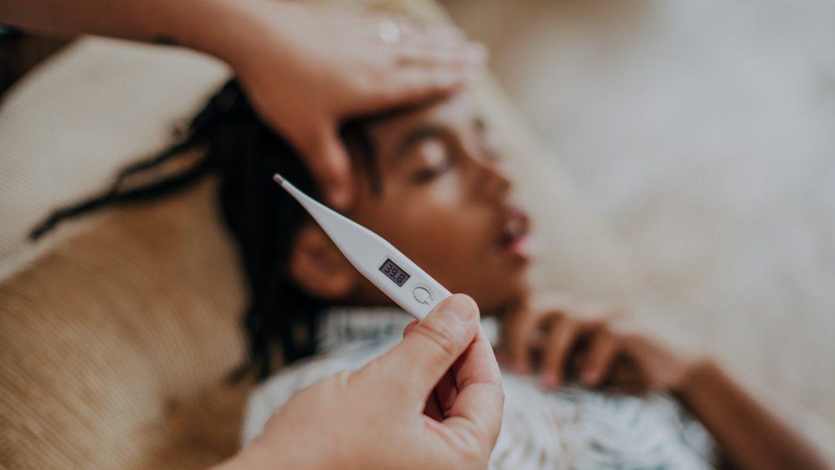 Criança desfocada deitada no sofá; foco está em termômetro 