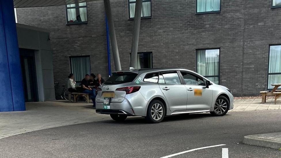Un taxi gris frente a un edificio sin identificar
